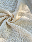 Tissu en coton froissé extensible neutre, surface texturée, tissu en coton ivoire blanc cassé, aspect tricoté.
