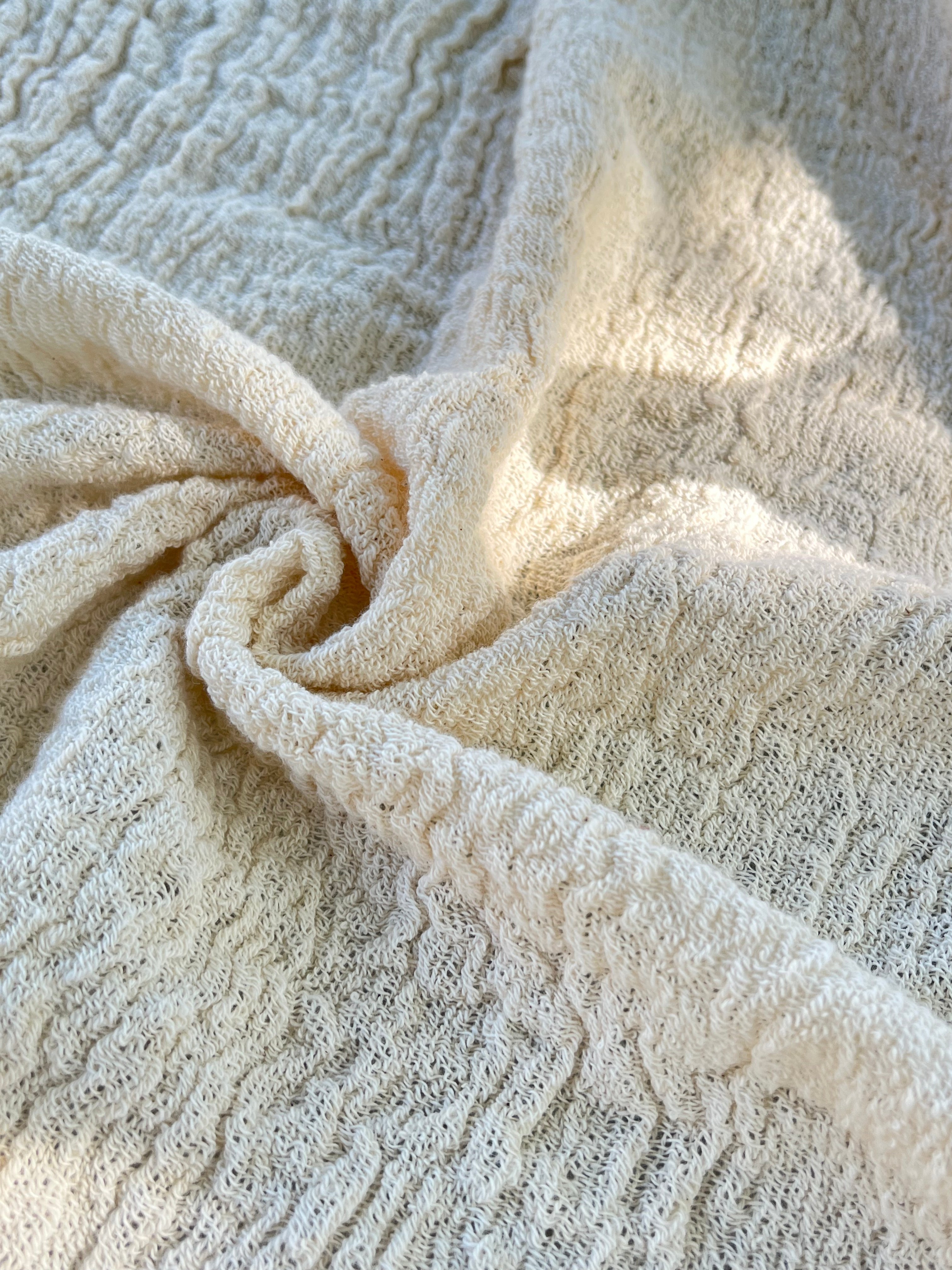 Tissu en coton froissé extensible neutre, surface texturée, tissu en coton ivoire blanc cassé, aspect tricoté.