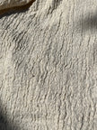 Tissu en coton froissé extensible neutre, surface texturée, tissu en coton ivoire blanc cassé, aspect tricoté.