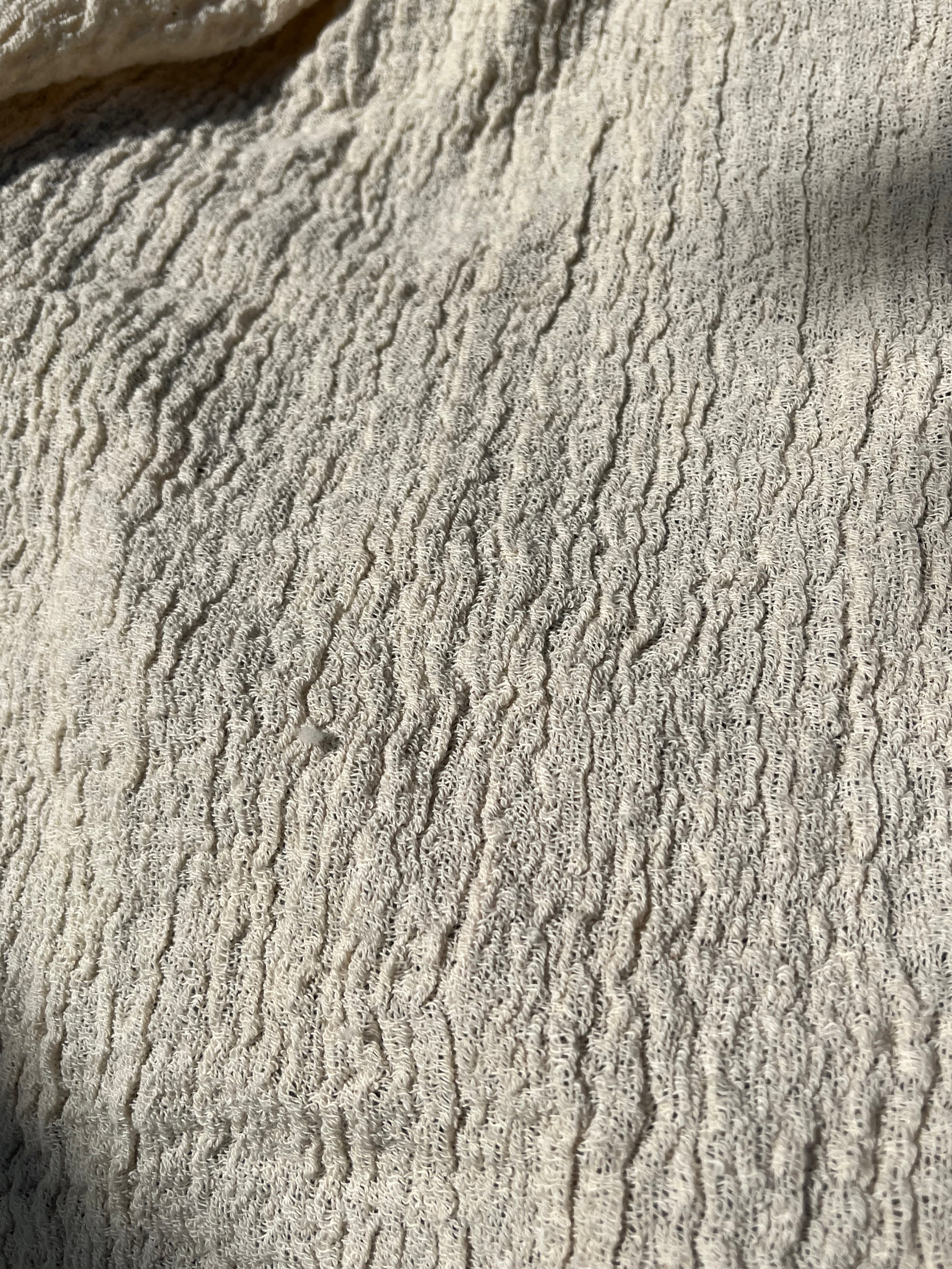 Tissu en coton froissé extensible neutre, surface texturée, tissu en coton ivoire blanc cassé, aspect tricoté.