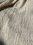 Tissu en coton froissé extensible neutre, surface texturée, tissu en coton ivoire blanc cassé, aspect tricoté.