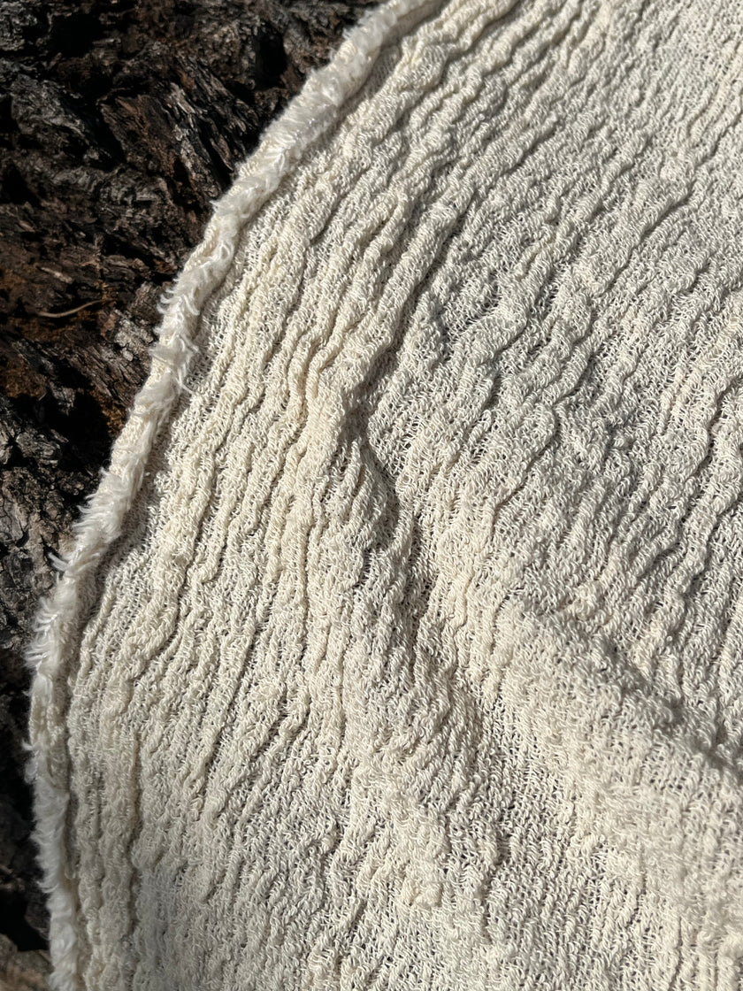 Tissu en coton froissé extensible neutre, surface texturée, tissu en coton ivoire blanc cassé, aspect tricoté.