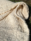 Tissu en coton froissé extensible neutre, surface texturée, tissu en coton ivoire blanc cassé, aspect tricoté.