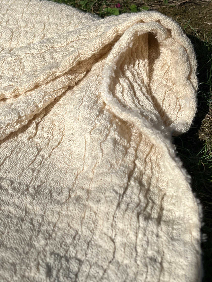 Tissu en coton froissé extensible neutre, surface texturée, tissu en coton ivoire blanc cassé, aspect tricoté.
