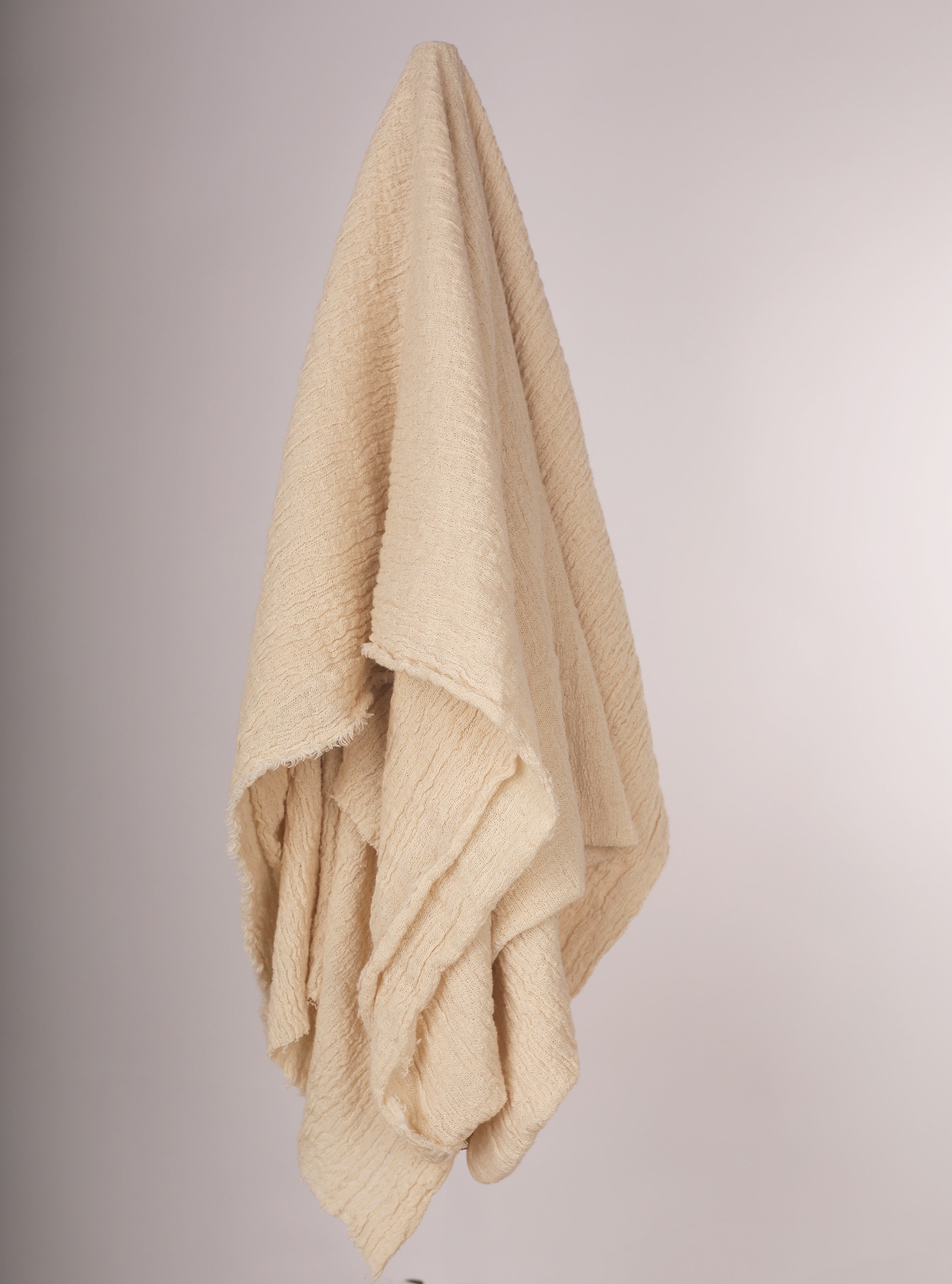 Tissu en coton froissé extensible neutre, surface texturée, tissu en coton ivoire blanc cassé, aspect tricoté.