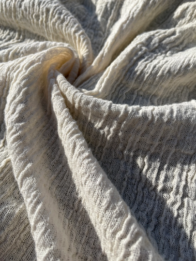Tissu en coton froissé extensible neutre, surface texturée, tissu en coton ivoire blanc cassé, aspect tricoté.